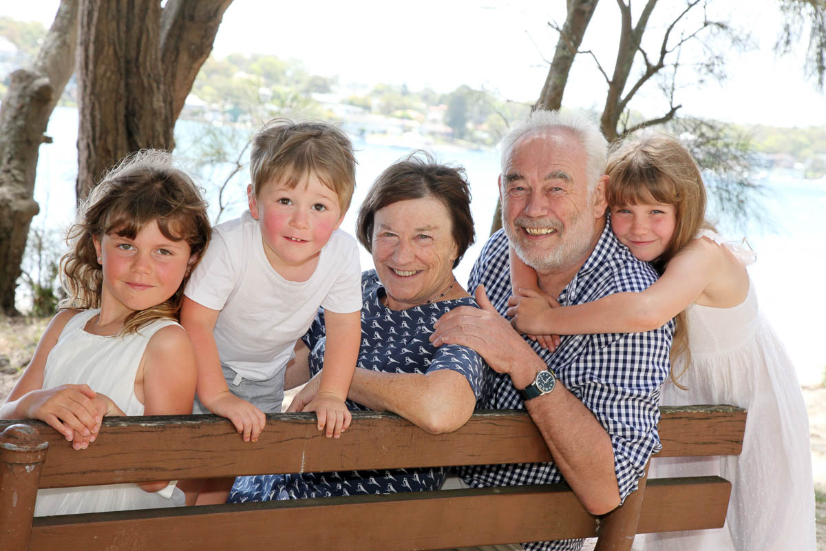 Grandparents sitting on a wooden bench surrounded by grandchildren during a family photoshoot with Southern Exposure Photography in the Sutherland Shire