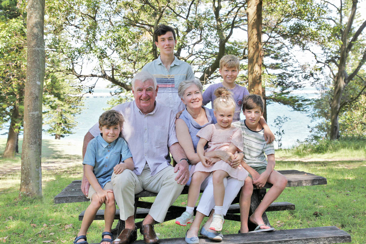 Grandparents sitting on a wooden bench surrounded by grandchildren during a family photoshoot with Southern Exposure Photography in the Sutherland Shire