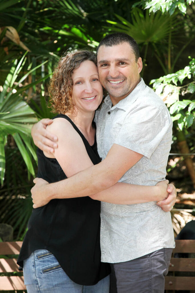 Couple embracing and smiling together in a lush green garden setting during an outdoor photoshoot with Southern Exposure Photography in the Sutherland Shire
