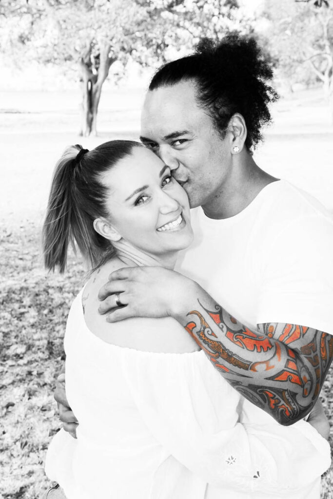 Couple embracing outdoors, with man kissing woman on the forehead during a romantic photoshoot with Southern Exposure Photography in the Sutherland Shire